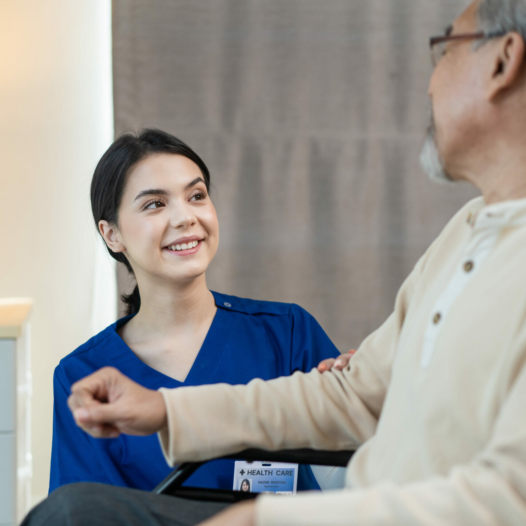 Asian nurse take care of senior man on wheelchair at nursing home care. Attractive happy Caregiver girl doctor greeting and talking with older elderly mature disabled patient male in hospital ward.